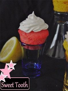 a cupcake with white frosting and a slice of lemon next to it on a table