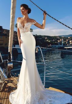 a woman standing on top of a boat wearing a white dress and holding her hand up