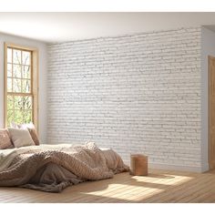 a bedroom with white brick walls and wood flooring is pictured in this image, there are pillows on the bed