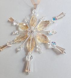 a snowflake ornament is shown on a white surface with blue and yellow beads