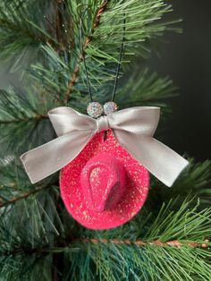 a pink hat ornament hanging from a pine tree