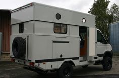 a white truck parked in front of a building next to a tall metal structure with windows