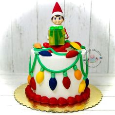 a birthday cake with an elf sitting on top of it