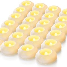 many lit candles are arranged in rows on a white surface