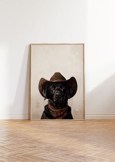 a black dog wearing a cowboy hat sitting in front of a framed photograph on the wall