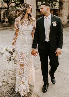 a bride and groom walking down the street holding hands