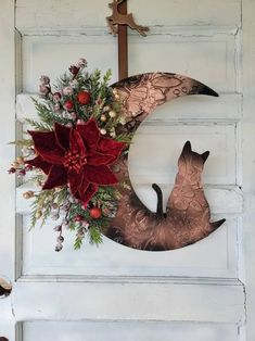 a door with a wreath and a cat sitting on the moon hanging from it's side