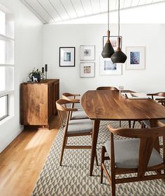 a dining room table and chairs in front of a window with pictures on the wall