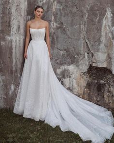 a woman standing in front of a stone wall wearing a white wedding dress and veil