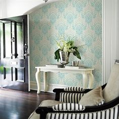 a vase with flowers sitting on a table in front of a door and a chair