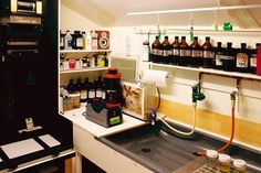 a kitchen sink filled with lots of bottles next to a shelf full of other items