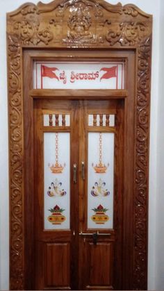 an ornate wooden door with two glass panels on the top and bottom panel, in front of a white wall