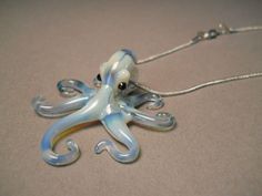 an octopus shaped glass necklace on a silver chain