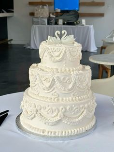 a three tiered wedding cake with swans on the top is sitting on a table