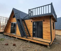 a small wooden house with stairs leading up to the roof