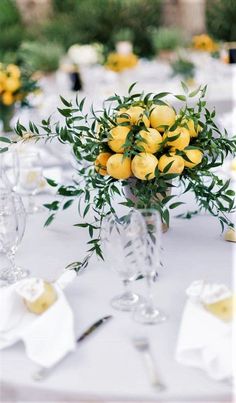 a vase filled with lemons sitting on top of a table next to white napkins