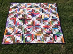 a patchwork quilt is laying on the grass