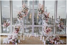 an arrangement of flowers and candles on display in front of a window with large windows