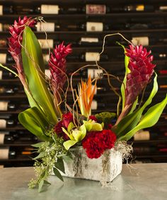 a vase filled with flowers and greenery on top of a table