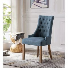 a blue chair sitting on top of a rug next to a wooden table and window