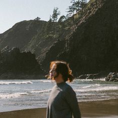 a man standing on top of a beach next to the ocean