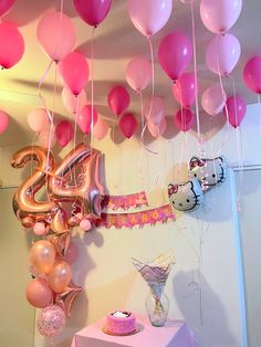 balloons and streamers are hanging from the ceiling above a table with a cake on it