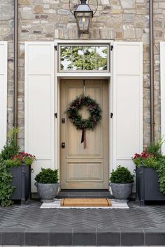 a front door with two planters and a wreath on it