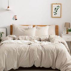 a bed with white and brown striped comforter in a room next to a nightstand