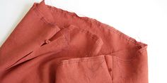 two pieces of red linen are laying on top of each other, with stitches in between them