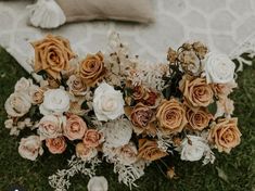 a bouquet of flowers sitting on top of a lush green field next to a pillow