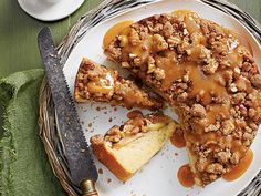 a white plate topped with cake covered in caramel sauce and toppings next to a knife