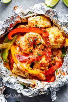 shrimp and peppers wrapped in tin foil with limes on the side for garnish