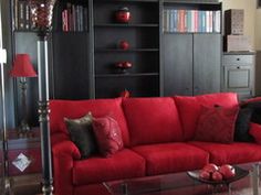 a living room with red couches and bookshelves