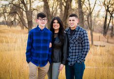 three people standing in front of trees and grass