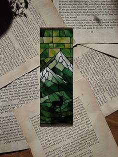 a stained glass piece sitting on top of an open book with some pages surrounding it