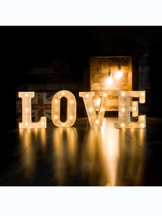 the word love is lit up with lights in front of a wooden box and candle