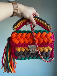 a woman's hand holding a multicolored purse