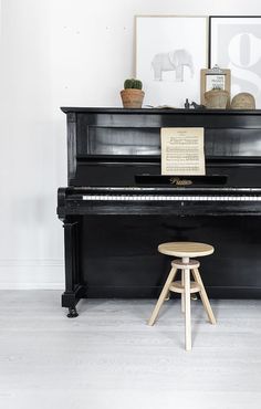 a black piano sitting on top of a hard wood floor next to a wooden stool