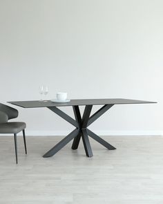 a glass table with two chairs next to it and a white wall in the background