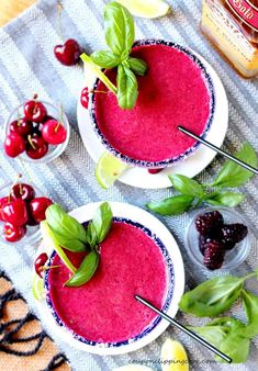 two bowls filled with cherries and garnishes on top of a table