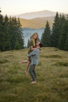 a man carrying a woman on his back in the middle of a field with trees