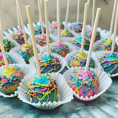 there are many cake pops with sprinkles on them and candy sticks sticking out of them