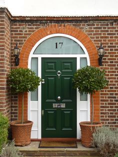 a green door with two potted plants in front of it