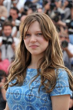 a woman with long brown hair standing in front of a group of people and taking pictures