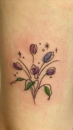 a small flower tattoo on the right side of the leg, it is purple and has green leaves