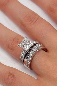 a woman's hand with two wedding rings on top of her finger and the other ring