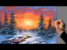 a person is holding a paintbrush and painting a sunset in the snow with pine trees