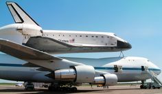 the space shuttle is sitting on top of an airplane's back end as it sits on the tarmac