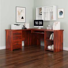 a wooden desk topped with a computer monitor next to a white shelf filled with books