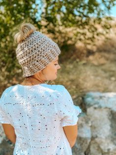 a woman wearing a crochet hat standing in front of some rocks